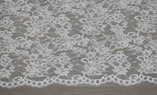 Encaje floral blanco con cordón en relieve y borde festoneado con ojales redondos