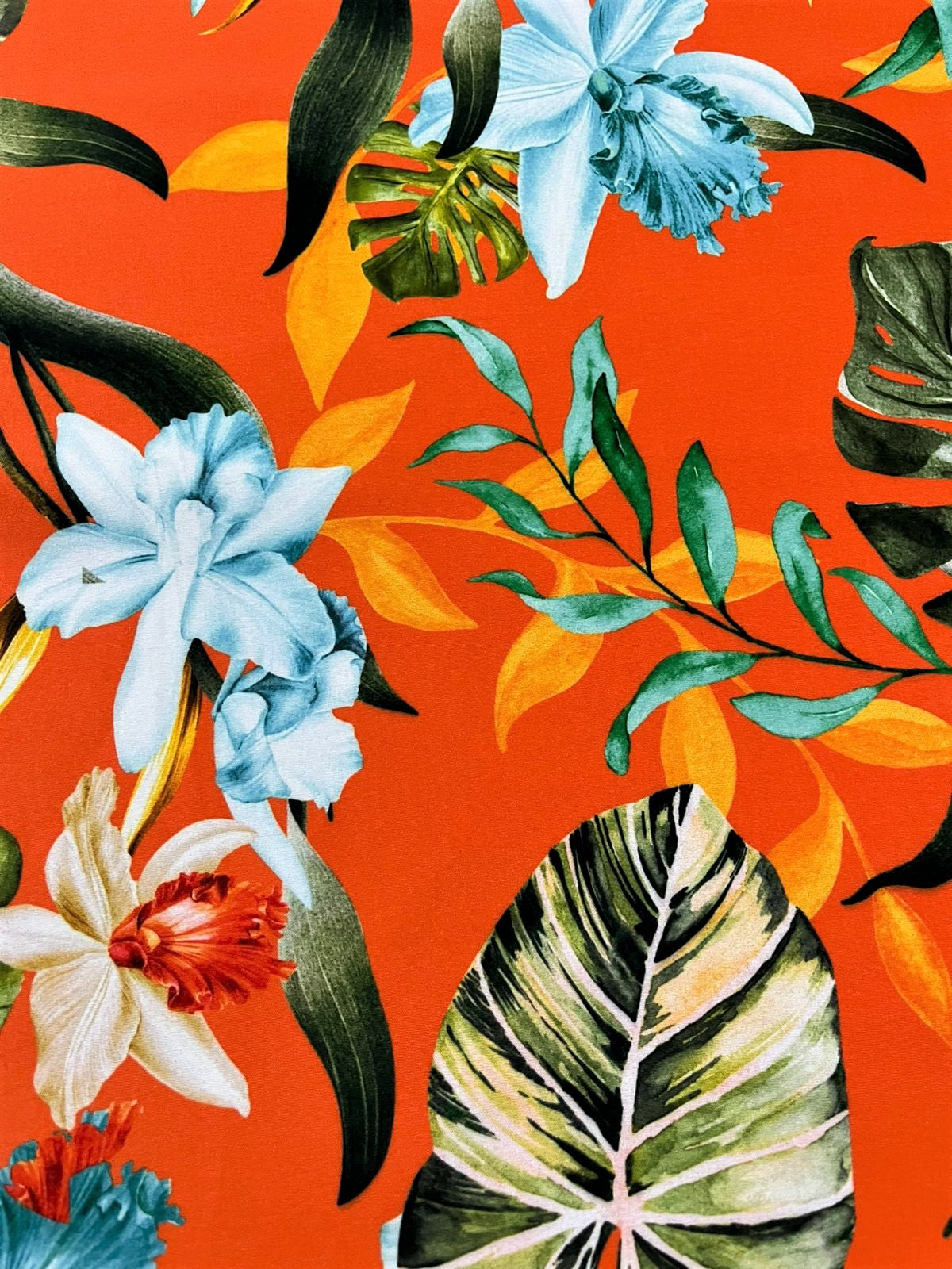 Detalle de seda francesa con orquídea celeste, hoja de nervaduras marcadas y ramas verde agua sobre naranja