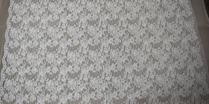 Vista completa del encaje floral blanco con cordón y borde festoneado con ojales en un lado