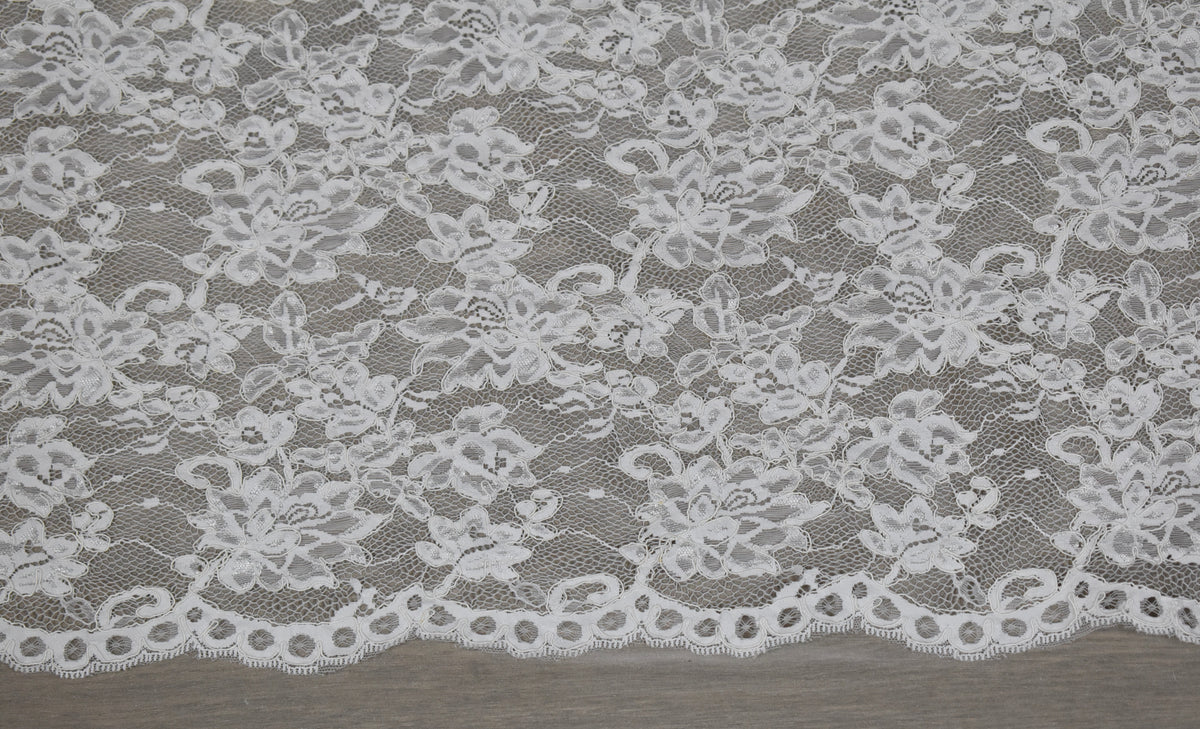 Encaje floral blanco con cordón en relieve y borde festoneado con ojales redondos