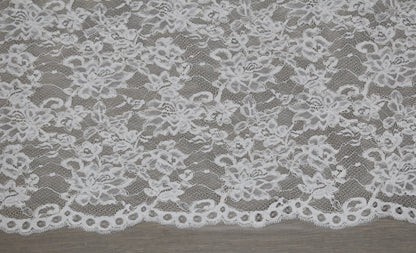 Encaje floral blanco con cordón en relieve y borde festoneado con ojales redondos