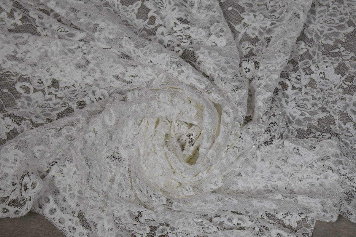 Encaje blanco con flores de cordón drapeado, mostrando su textura y transparencia
