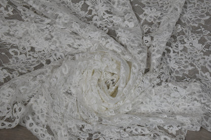 Encaje blanco con flores de cordón drapeado, mostrando su textura y transparencia