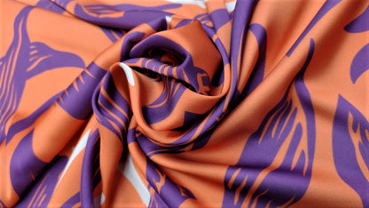 Seda francesa de hojas moradas sobre naranja salmón drapeada, mostrando su brillo y caída fluida