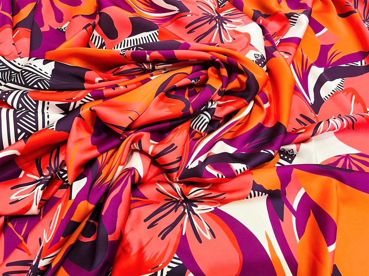 Seda francesa tropical fucsia, naranja y coral drapeada, mostrando su brillo y caída fluida