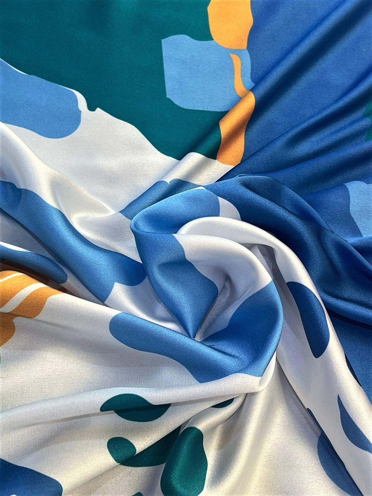 Seda francesa abstracta azul, verde y mostaza sobre marfil drapeada, mostrando su brillo y caída fluida