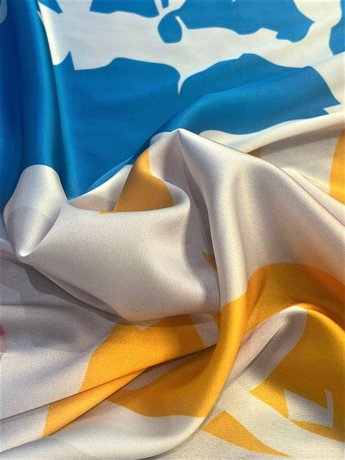 Seda francesa abstracta azul cielo y mostaza drapeada, mostrando su brillo y caída fluida