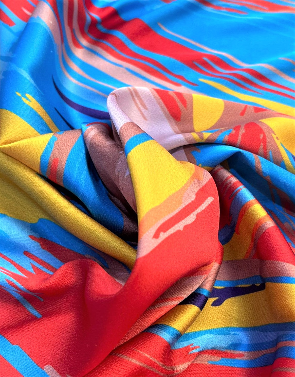 Seda francesa de pinceladas rojo, amarillo y azul drapeada, mostrando su brillo y caída fluida