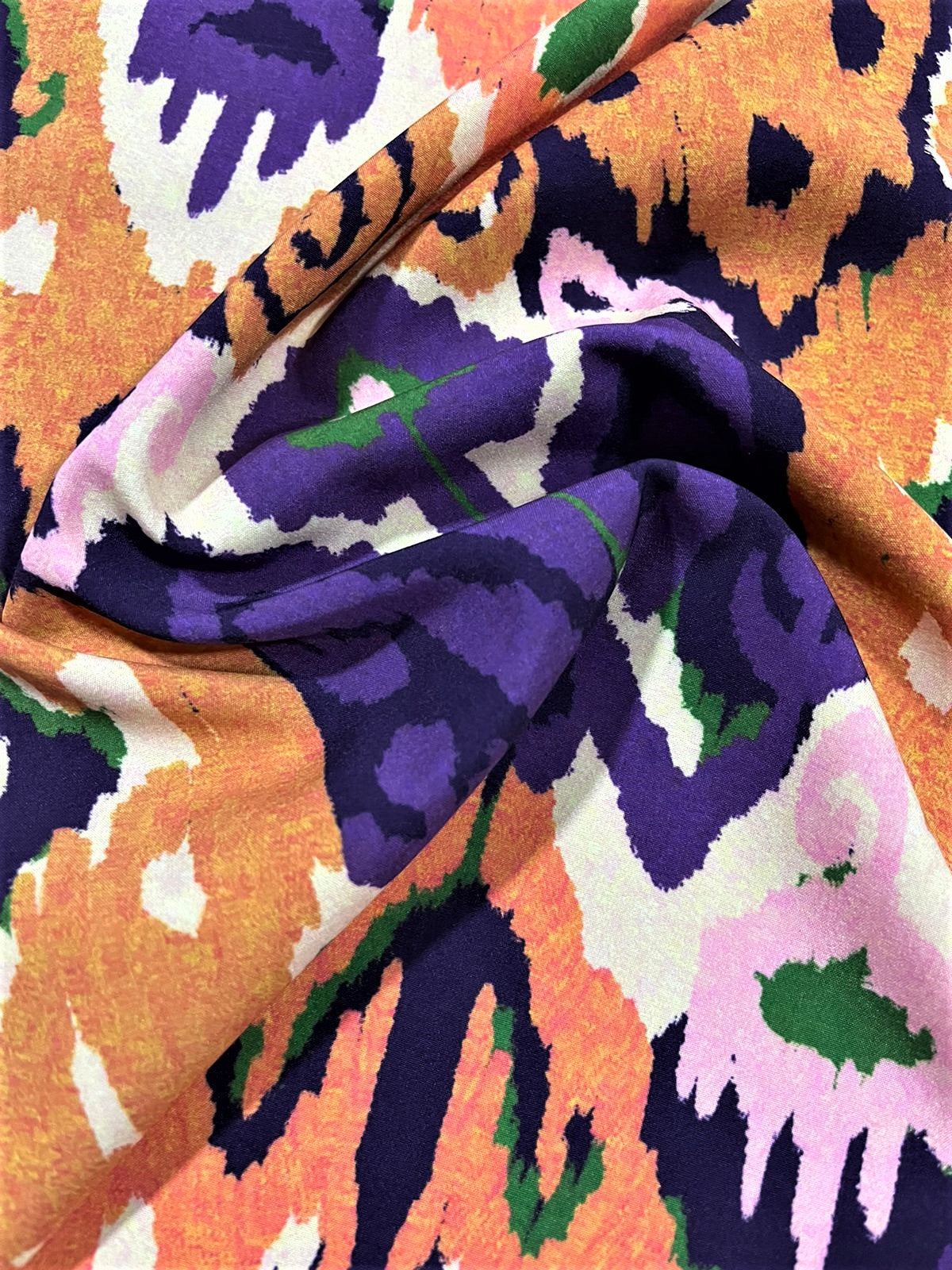 Seda francesa ikat morado y naranja drapeada, mostrando su brillo y caída fluida