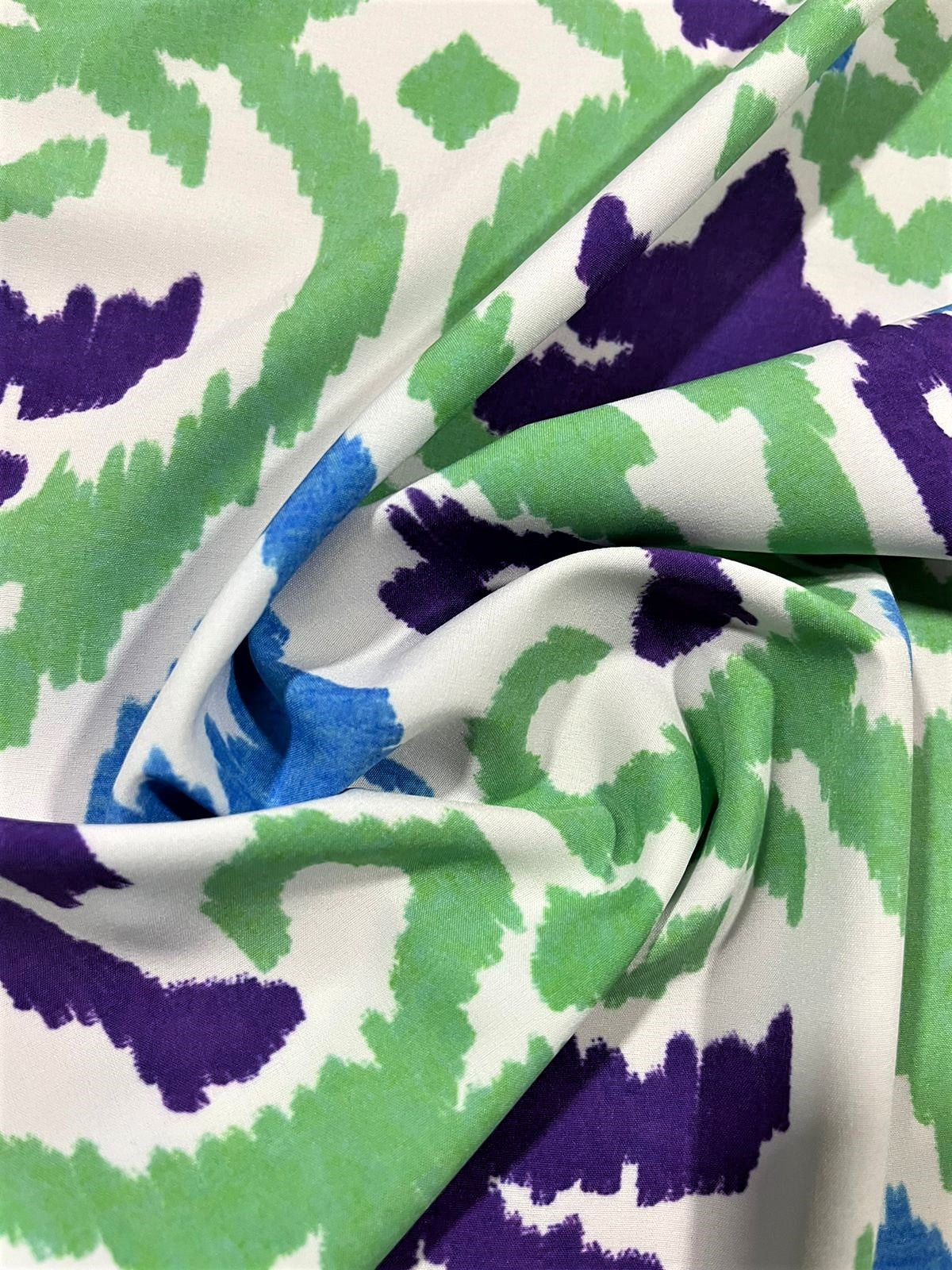 Seda francesa ikat verde y morado drapeada, mostrando su brillo y caída fluida