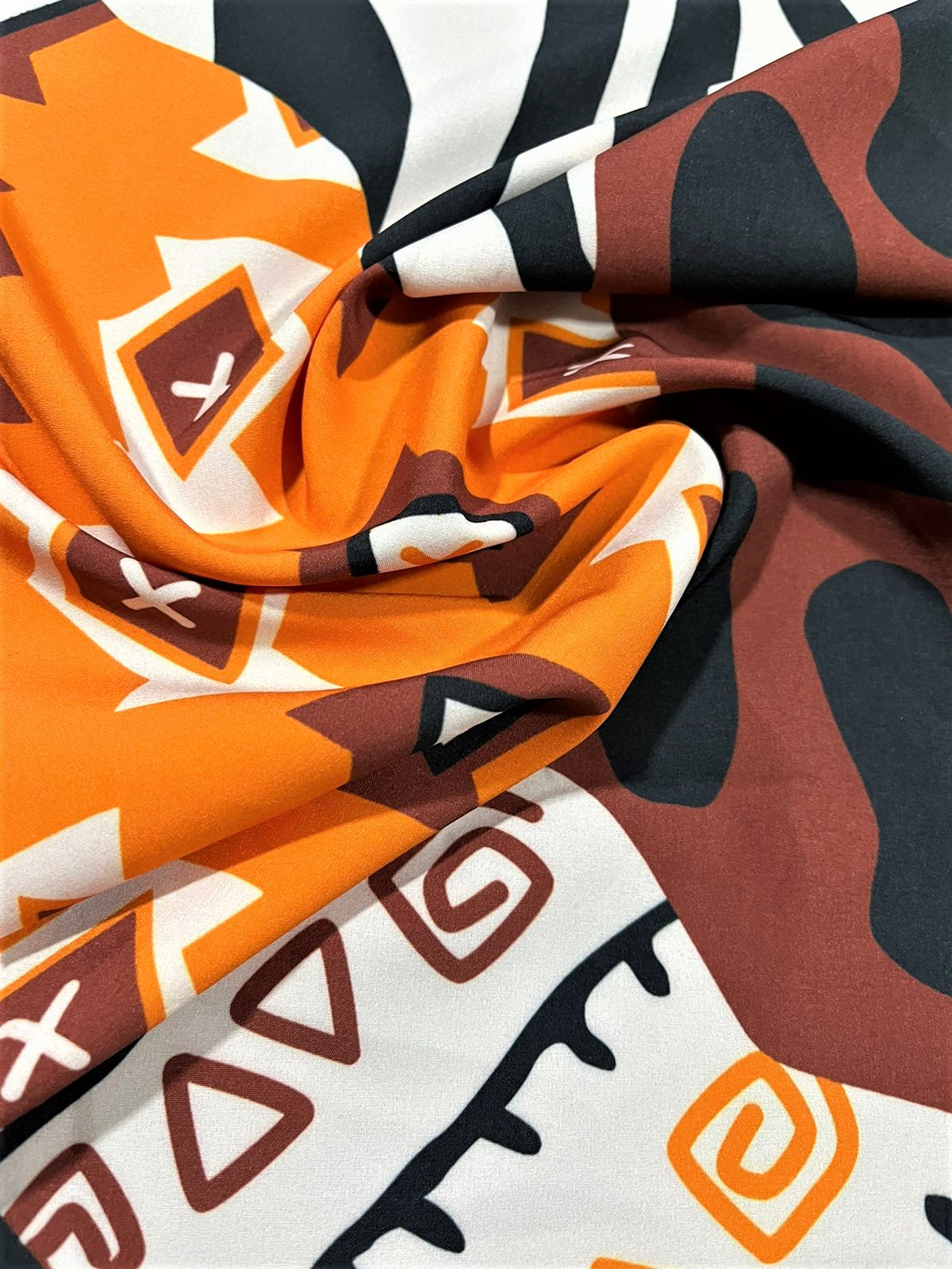 Seda francesa étnica naranja, café y animal print drapeada, mostrando su brillo y caída fluida