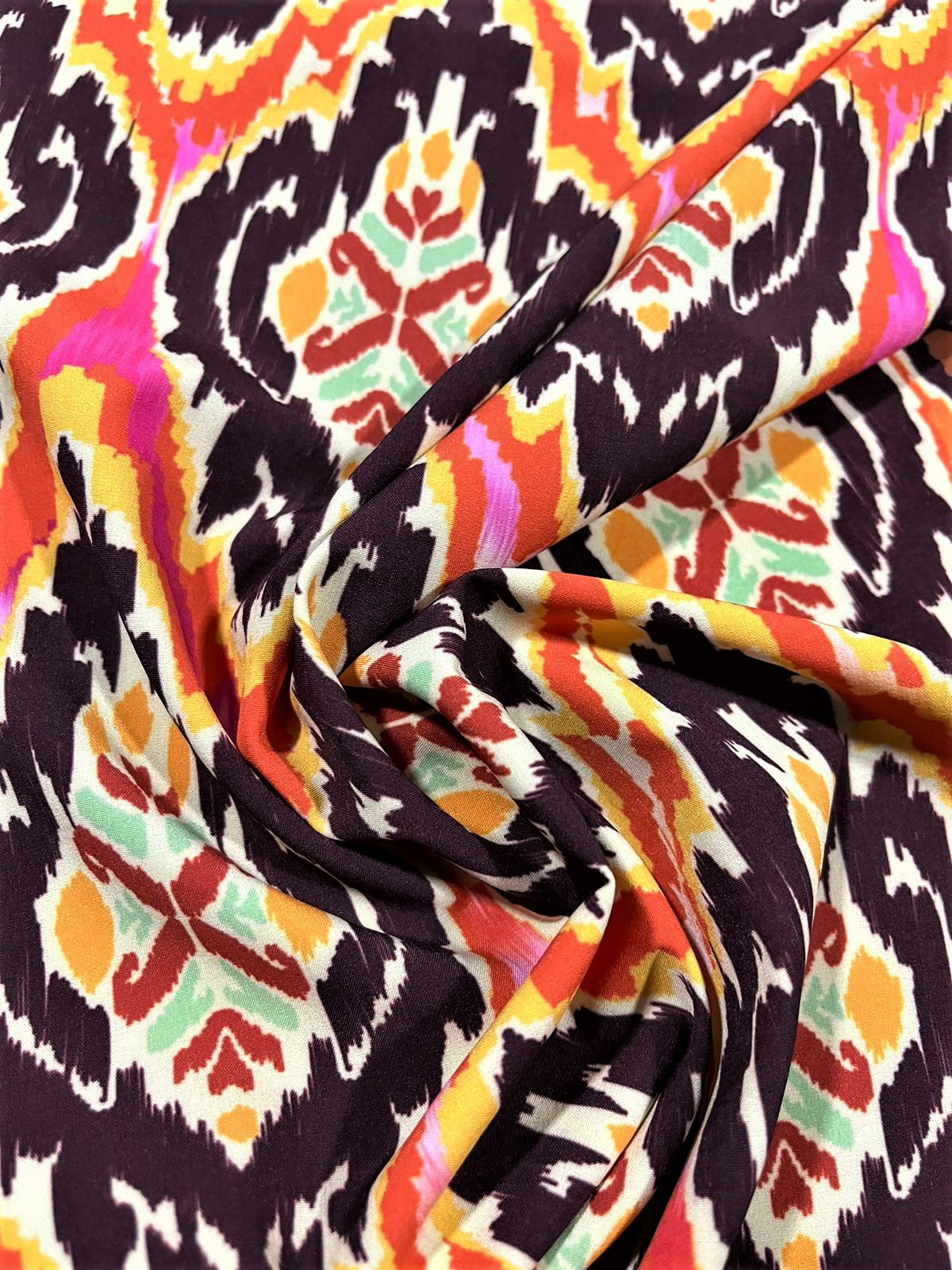 Seda francesa ikat vino, naranja y amarillo drapeada, mostrando su brillo y caída fluida