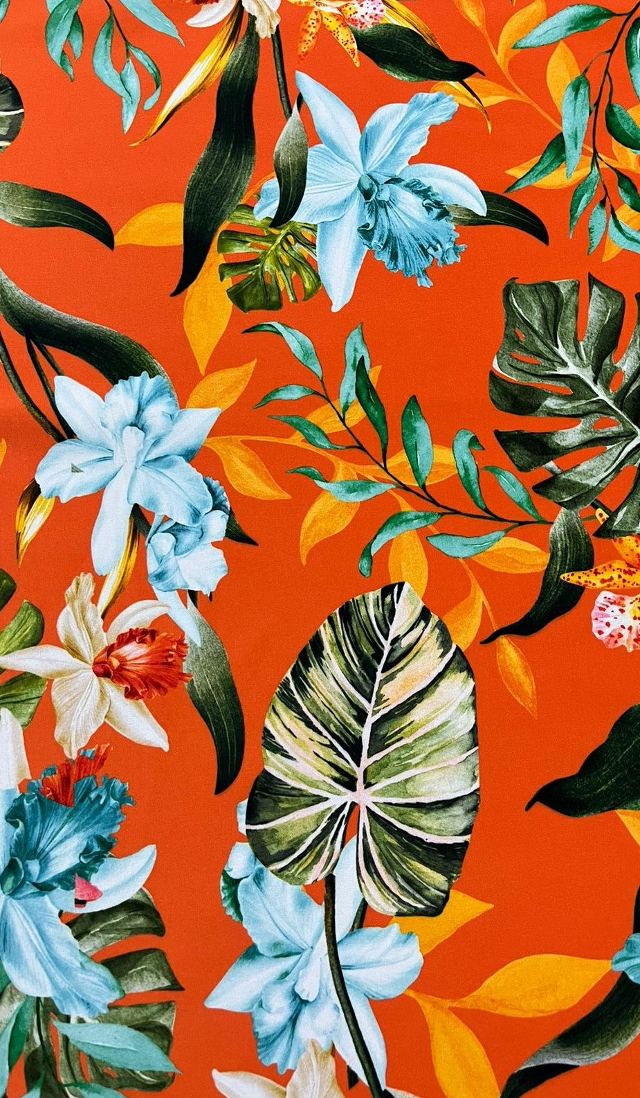 Seda francesa con estampado de orquídeas celeste y blancas, monstera y follaje tropical sobre fondo naranja