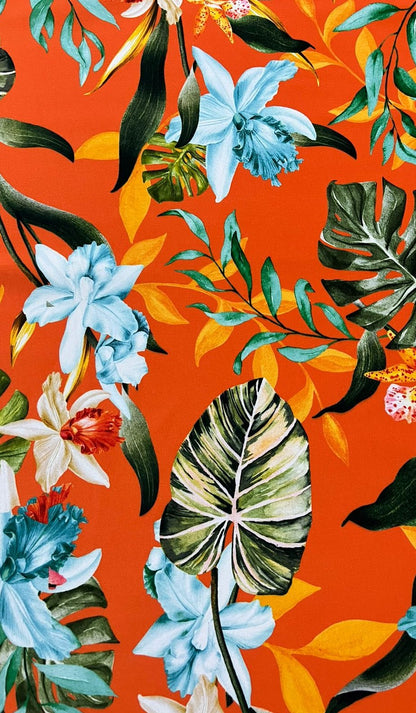 Seda francesa con estampado de orquídeas celeste y blancas, monstera y follaje tropical sobre fondo naranja