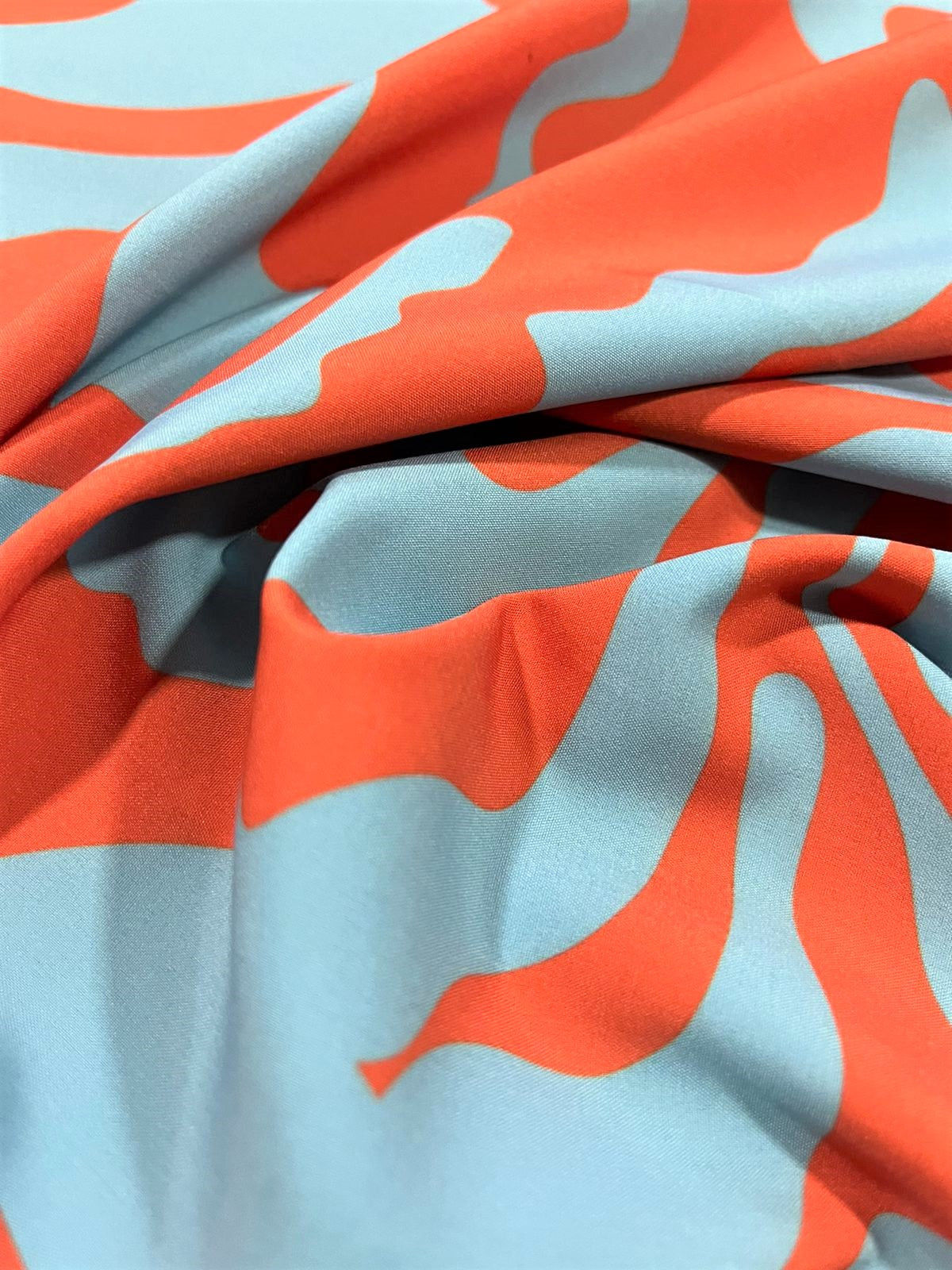 Seda francesa abstracta azul agua y naranja drapeada, mostrando su brillo y caída fluida