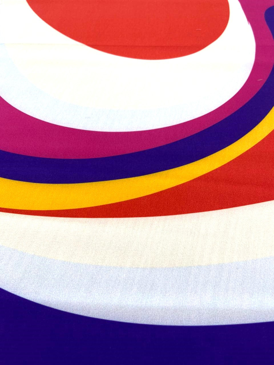 Detalle de seda francesa con franjas curvas en fucsia, morado, amarillo y rojo sobre blanco