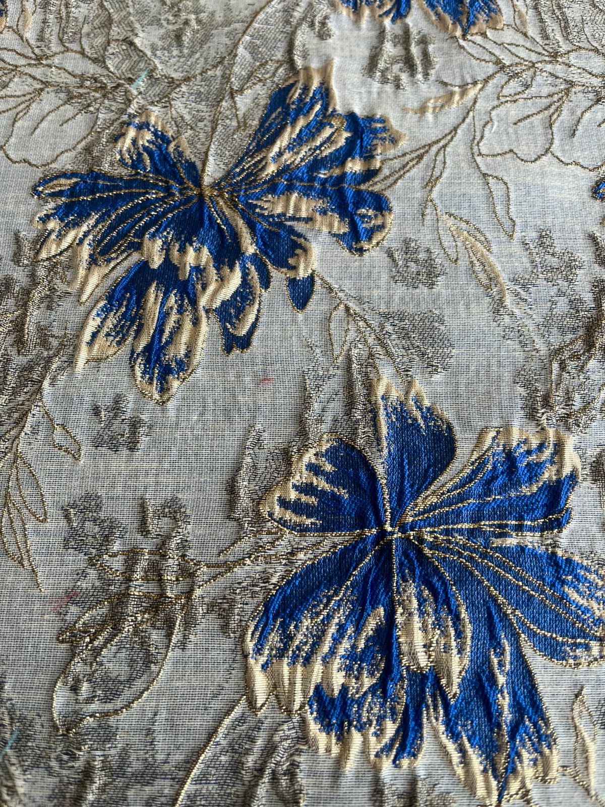 Vista superior de estampado floral azul rey y dorado en jacquard sobre fondo claro