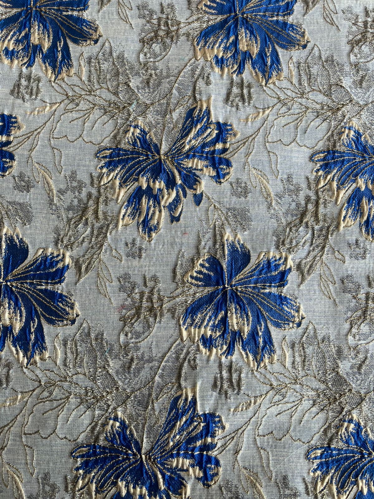 Primer plano de flor azul y dorada con contorno metalizado en jacquard blanco