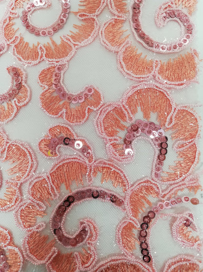 Detalle de flor coral con contorno rosa y espiral de lentejuelas sobre tul claro