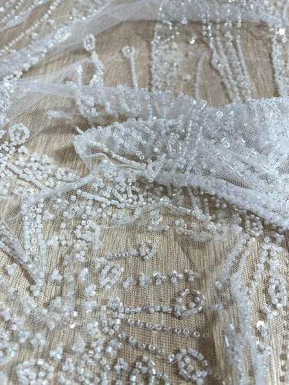 Primer plano de pedrería bordada sobre tul beige transparente